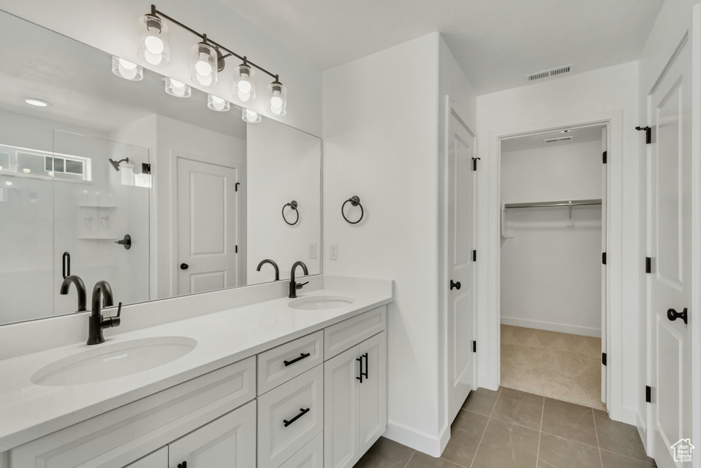 Bathroom with double sink, tile flooring, and vanity with extensive cabinet space