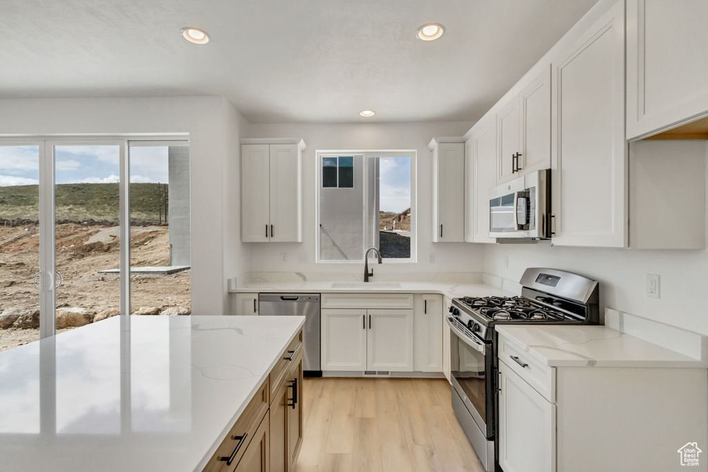 Kitchen featuring appliances with stainless steel finishes, white cabinetry, sink, and light hardwood / wood-style flooring