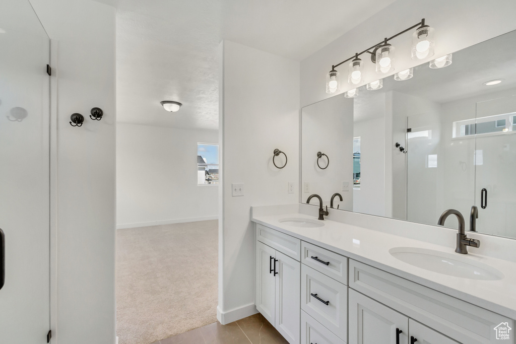 Bathroom featuring tile flooring, dual sinks, an enclosed shower, and vanity with extensive cabinet space