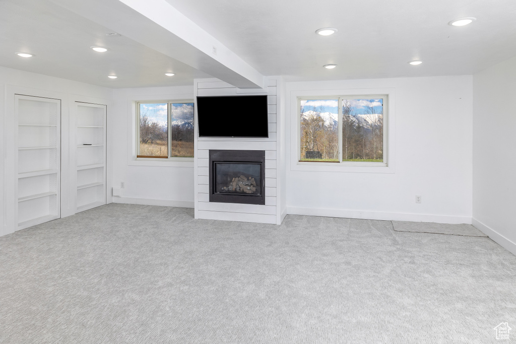 Unfurnished living room featuring light carpet and a large fireplace