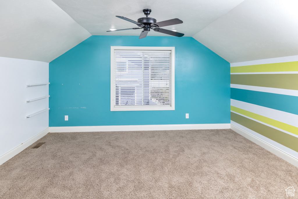 Additional living space with ceiling fan, lofted ceiling, and light colored carpet
