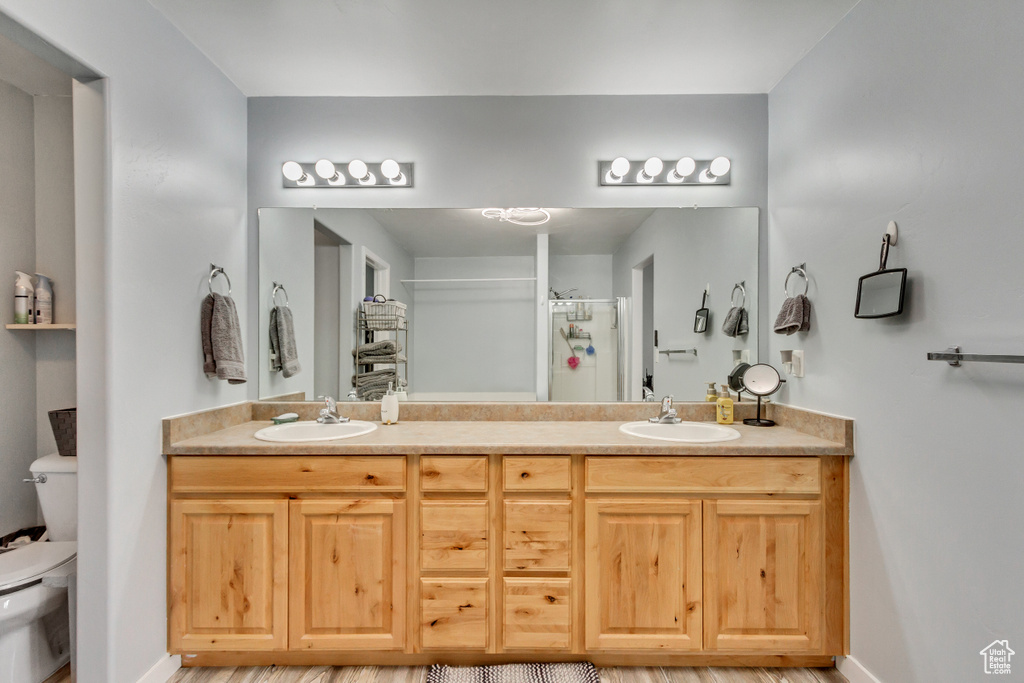 Bathroom with hardwood / wood-style flooring, double vanity, and toilet