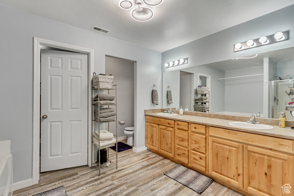 Bathroom featuring double sink vanity, toilet, and hardwood / wood-style flooring