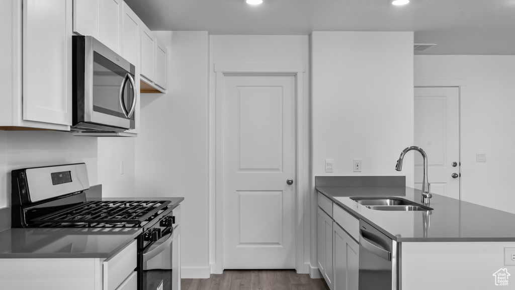 Kitchen featuring white cabinetry, hardwood / wood-style floors, appliances with stainless steel finishes, and sink