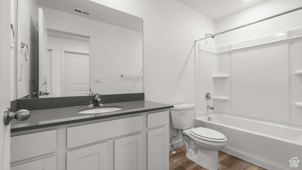 Full bathroom with toilet, large vanity, hardwood / wood-style floors, and tub / shower combination
