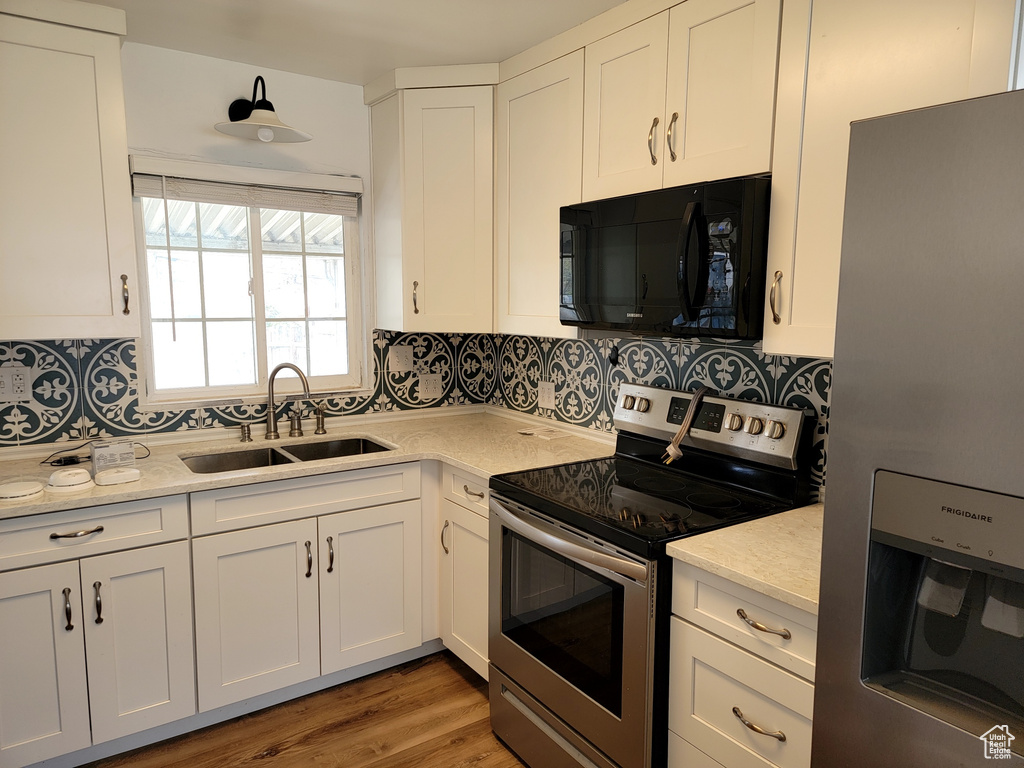 Kitchen with backsplash, white cabinets, appliances with stainless steel finishes, and sink