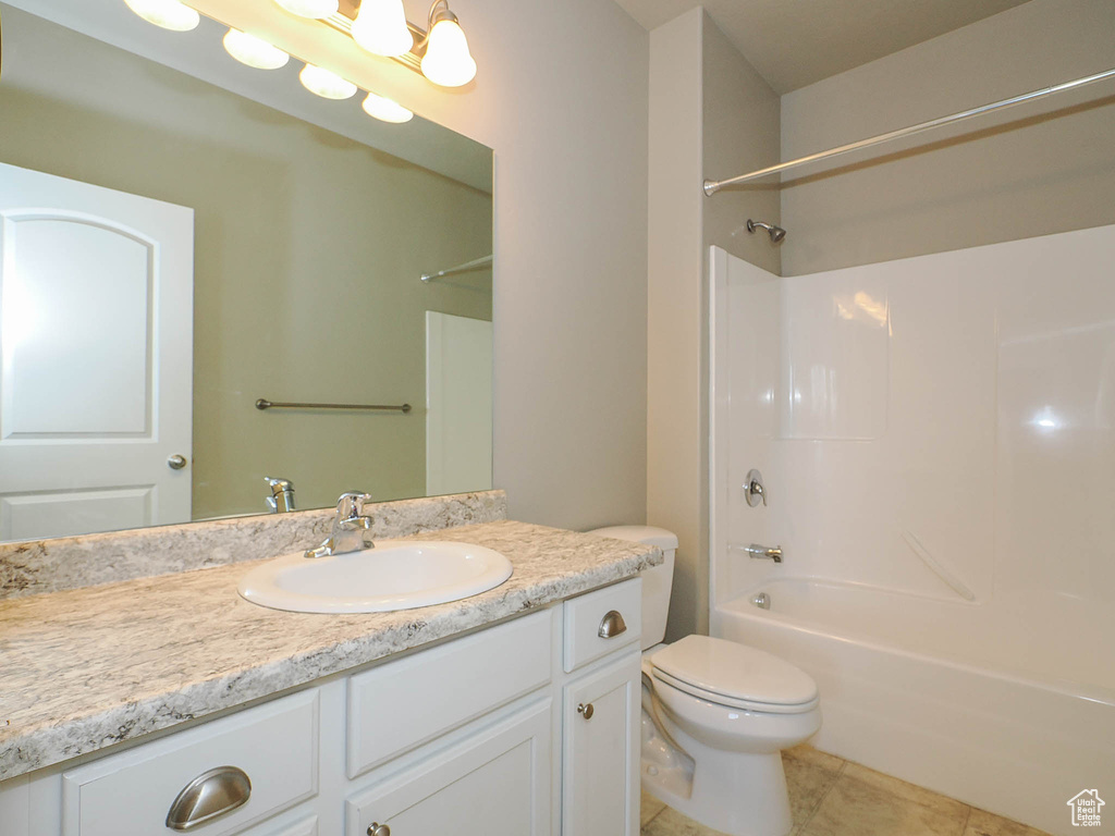 Full bathroom featuring tile flooring, toilet, large vanity, and shower / tub combination