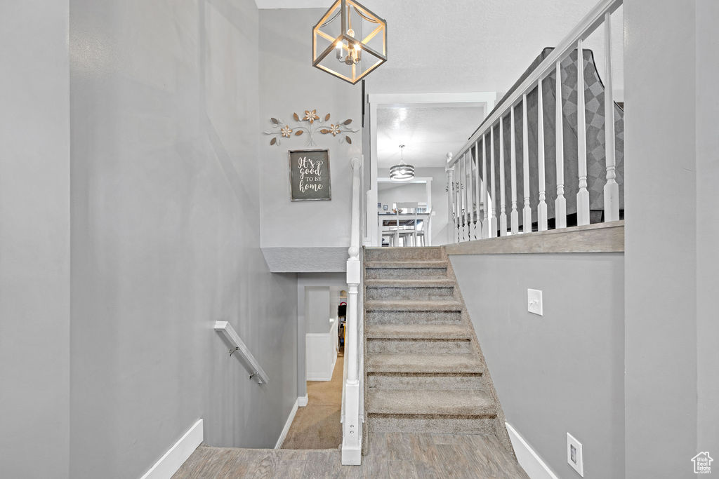 Stairway with an inviting chandelier and light tile floors