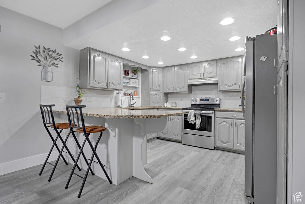 Kitchen featuring a breakfast bar, stainless steel appliances, kitchen peninsula, and light hardwood / wood-style floors