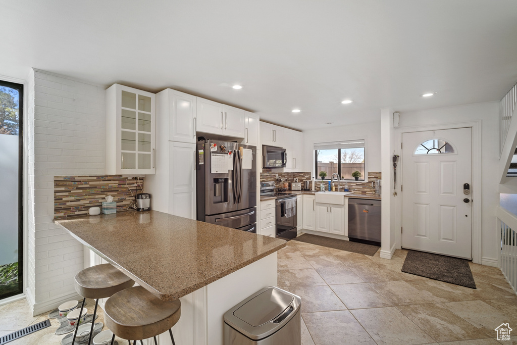 Kitchen with tasteful backsplash, a breakfast bar, appliances with stainless steel finishes, and white cabinetry