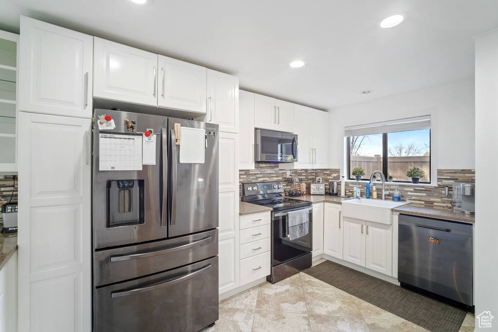 Kitchen featuring tasteful backsplash, stainless steel appliances, white cabinetry, and light tile floors