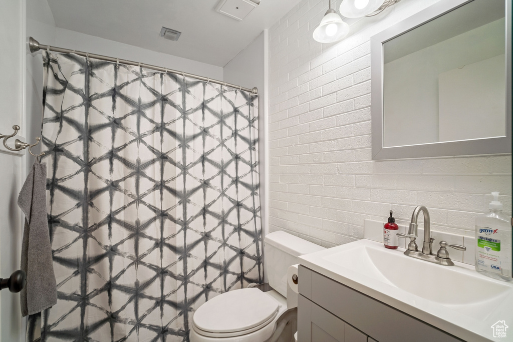 Bathroom featuring toilet, vanity, and tile walls