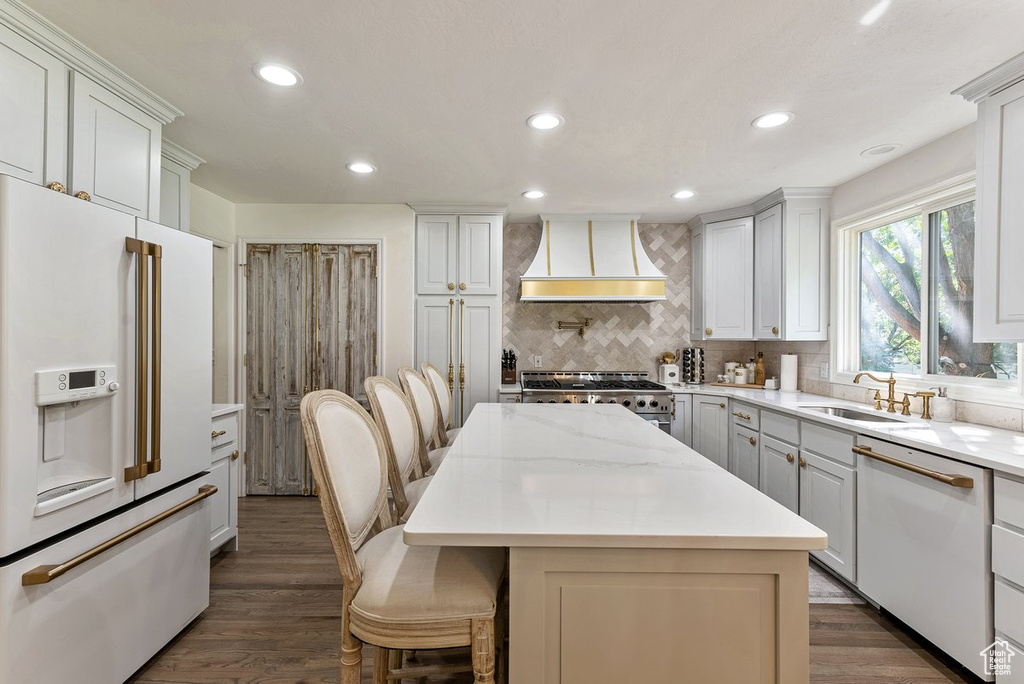 Kitchen with dark hardwood / wood-style flooring, a breakfast bar, high quality appliances, a kitchen island, and custom range hood