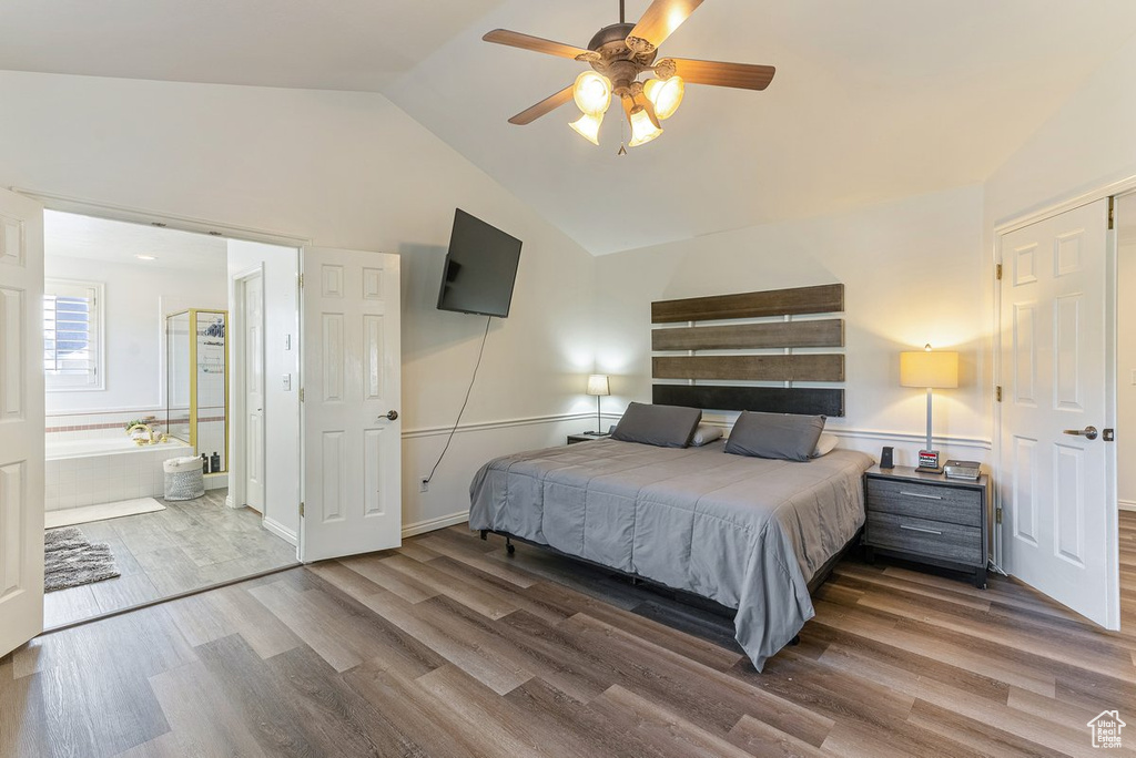 Bedroom with lofted ceiling, ceiling fan, dark wood-type flooring, and connected bathroom