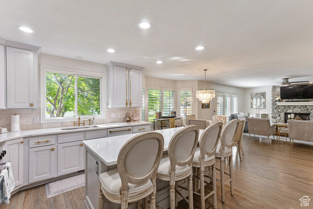 Kitchen with a notable chandelier, a wealth of natural light, a stone fireplace, and light hardwood / wood-style floors