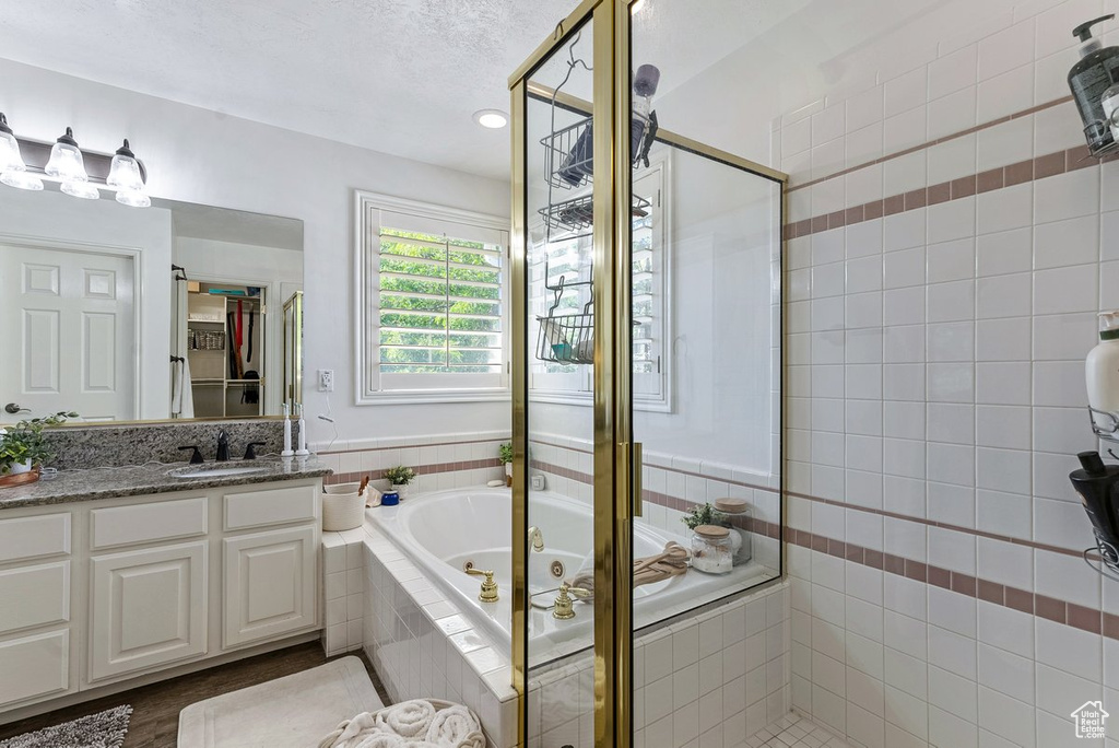 Bathroom featuring shower with separate bathtub, a textured ceiling, hardwood / wood-style floors, and vanity