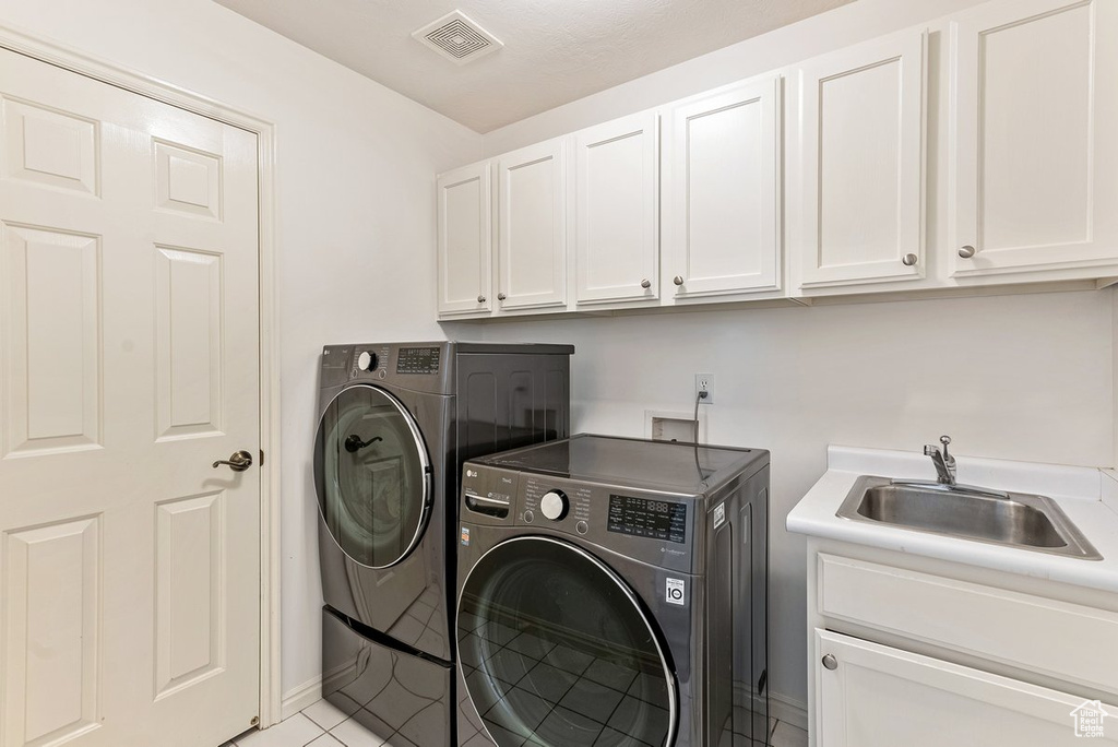 Clothes washing area with separate washer and dryer, light tile floors, washer hookup, cabinets, and sink