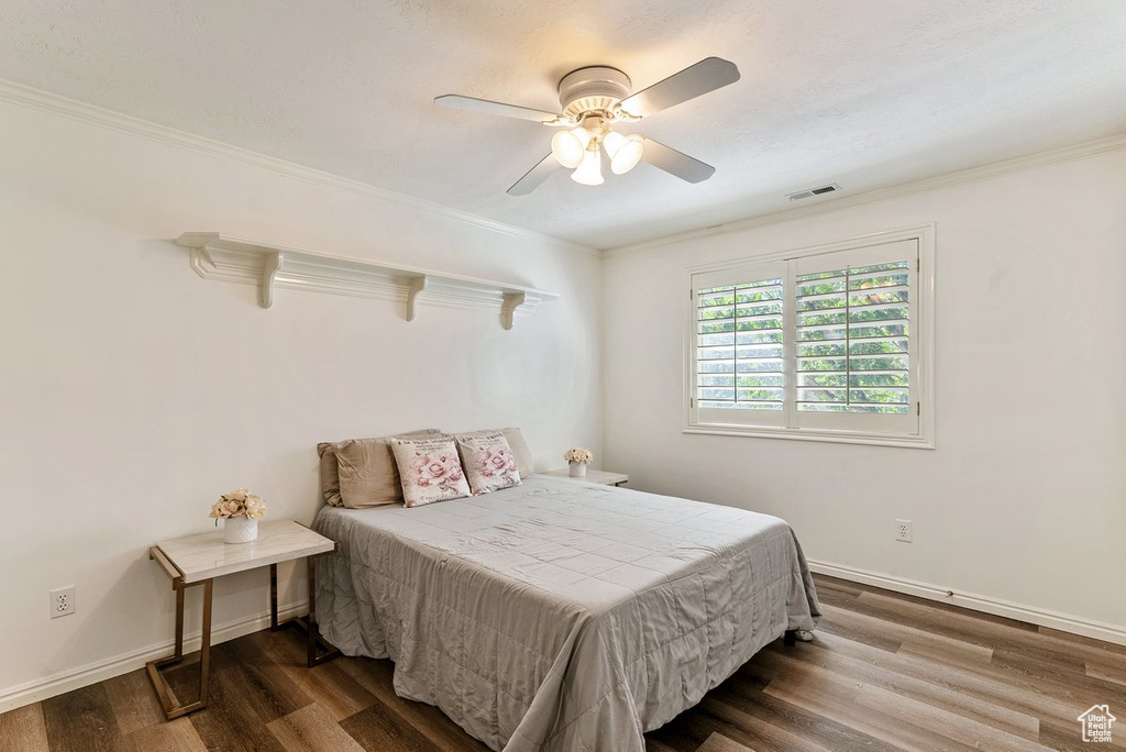 Bedroom featuring ceiling fan, dark hardwood / wood-style floors, and crown molding