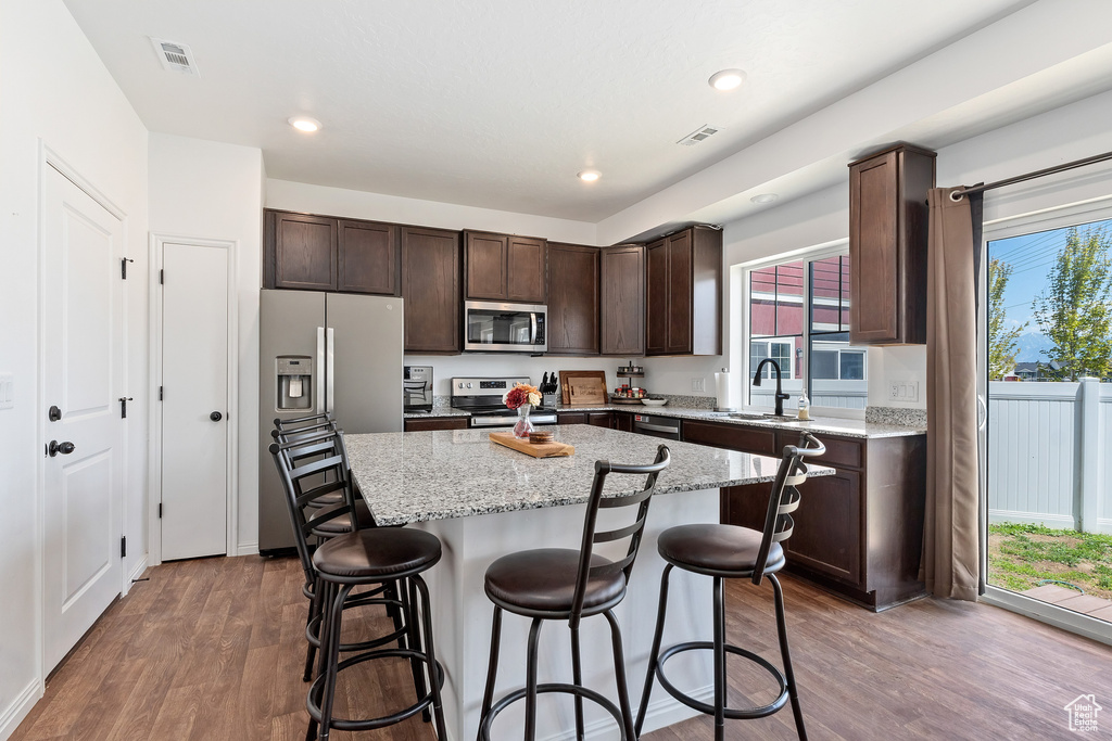 Kitchen with a center island, stainless steel appliances, dark wood-type flooring, and a wealth of natural light
