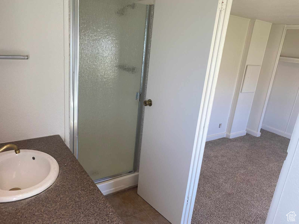 Bathroom featuring a shower with shower door, tile flooring, and sink