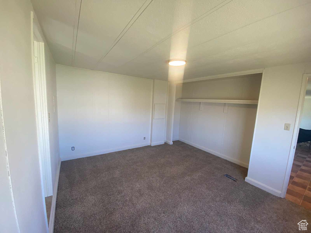 Unfurnished bedroom featuring a closet and dark colored carpet