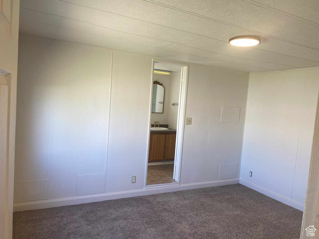 Unfurnished bedroom featuring dark carpet, a textured ceiling, and sink