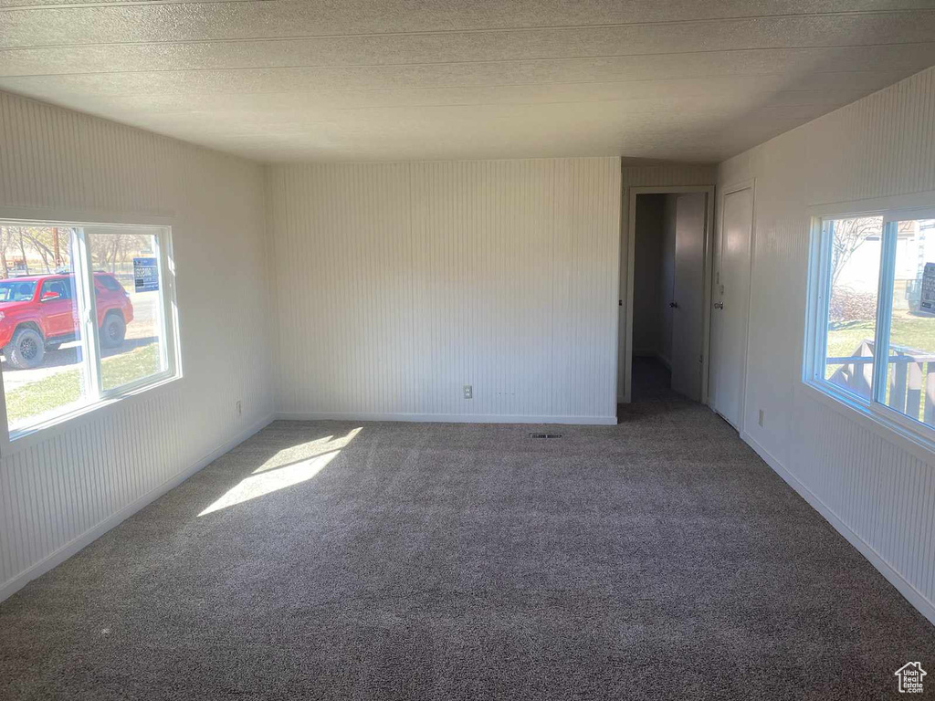 Unfurnished room with dark carpet and a textured ceiling