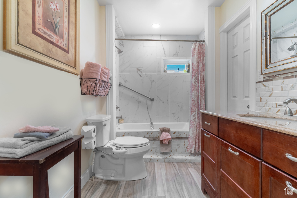 Full bathroom featuring toilet, backsplash, shower / bathtub combination with curtain, and vanity