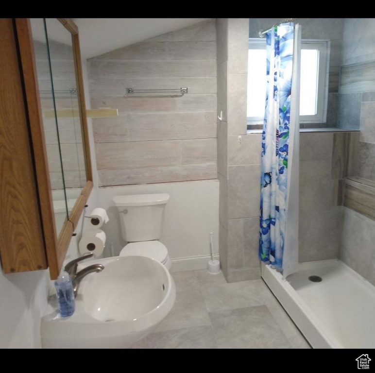Bathroom featuring tile flooring, sink, walk in shower, lofted ceiling, and toilet
