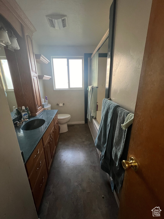 Bathroom with a shower with shower door, vanity, toilet, and tile flooring