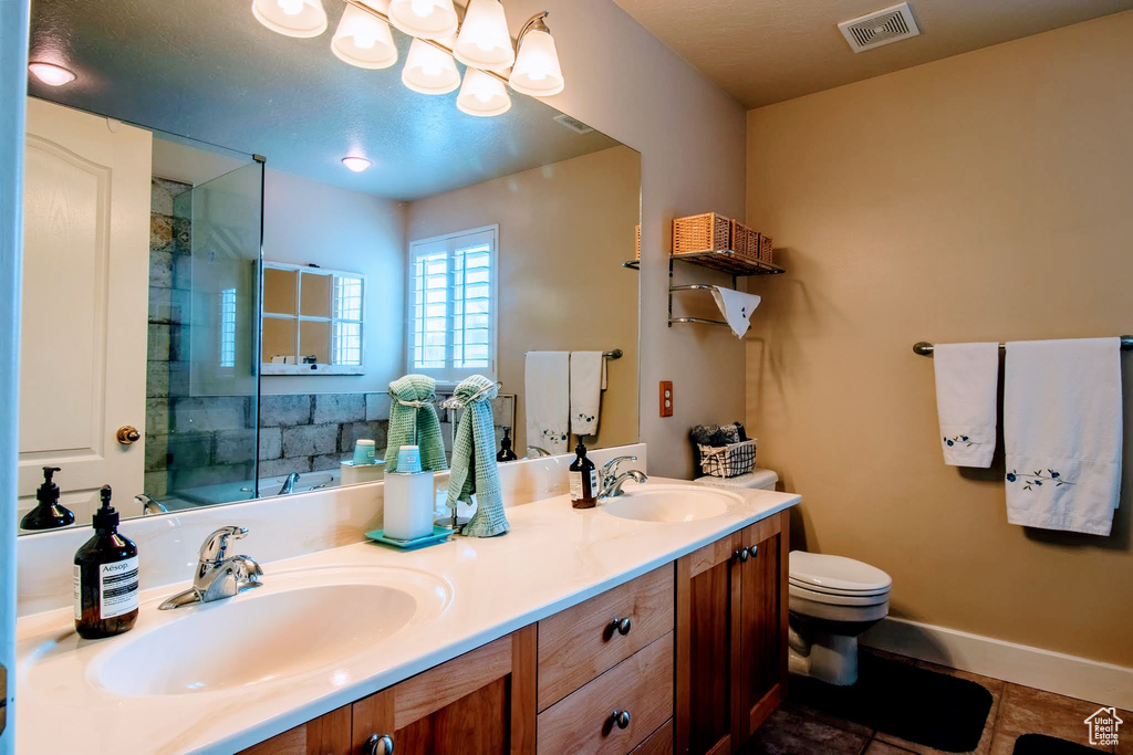 Bathroom featuring toilet, dual bowl vanity, and tile flooring