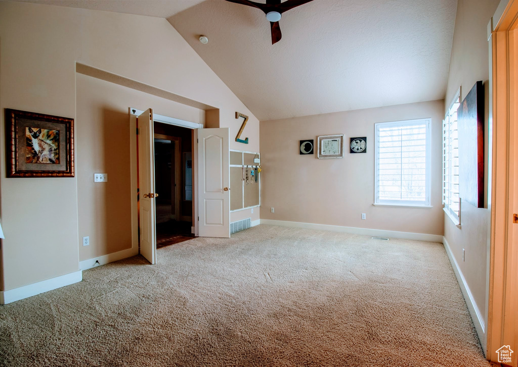 Unfurnished bedroom with ceiling fan, lofted ceiling, and light colored carpet