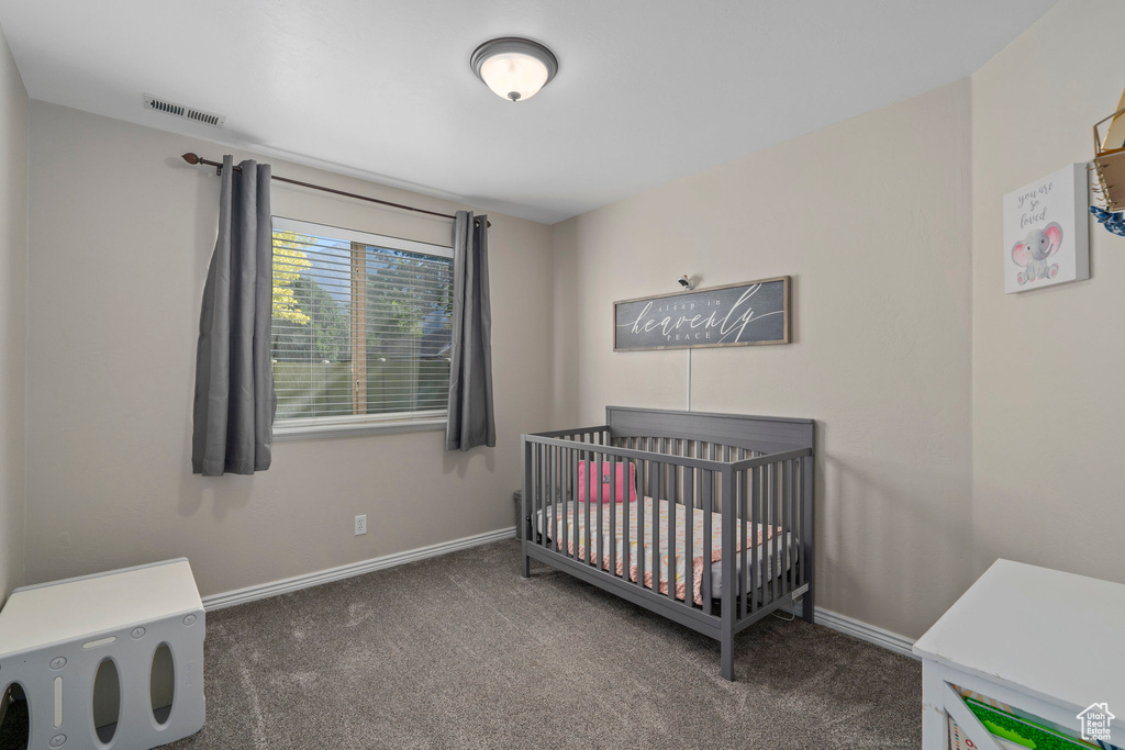Bedroom featuring a crib and dark colored carpet
