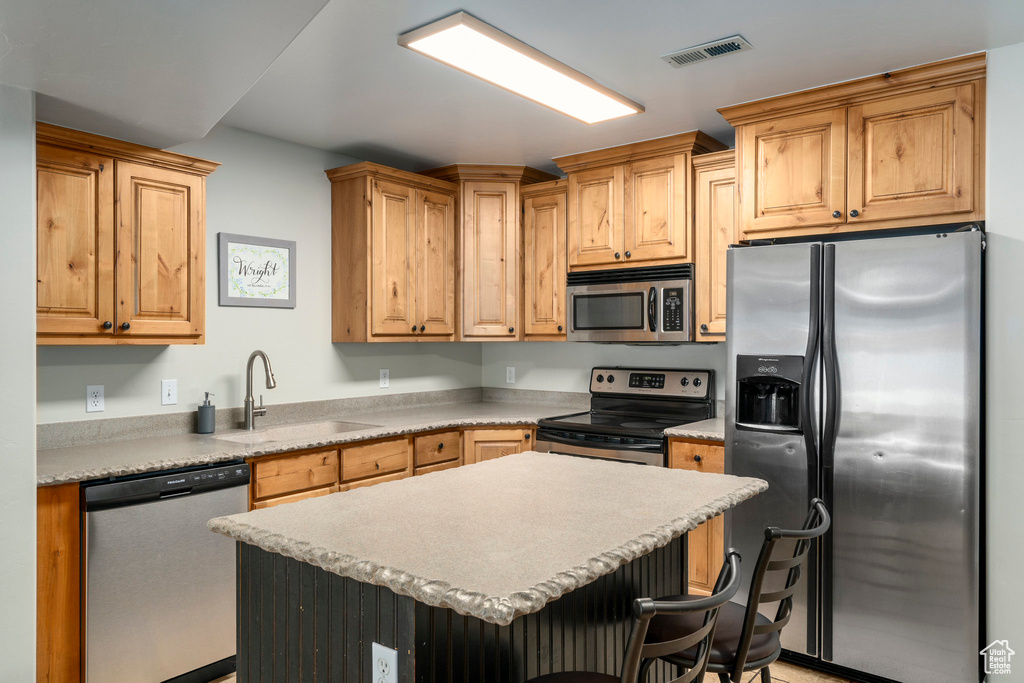 Kitchen with a breakfast bar, sink, stainless steel appliances, and a center island