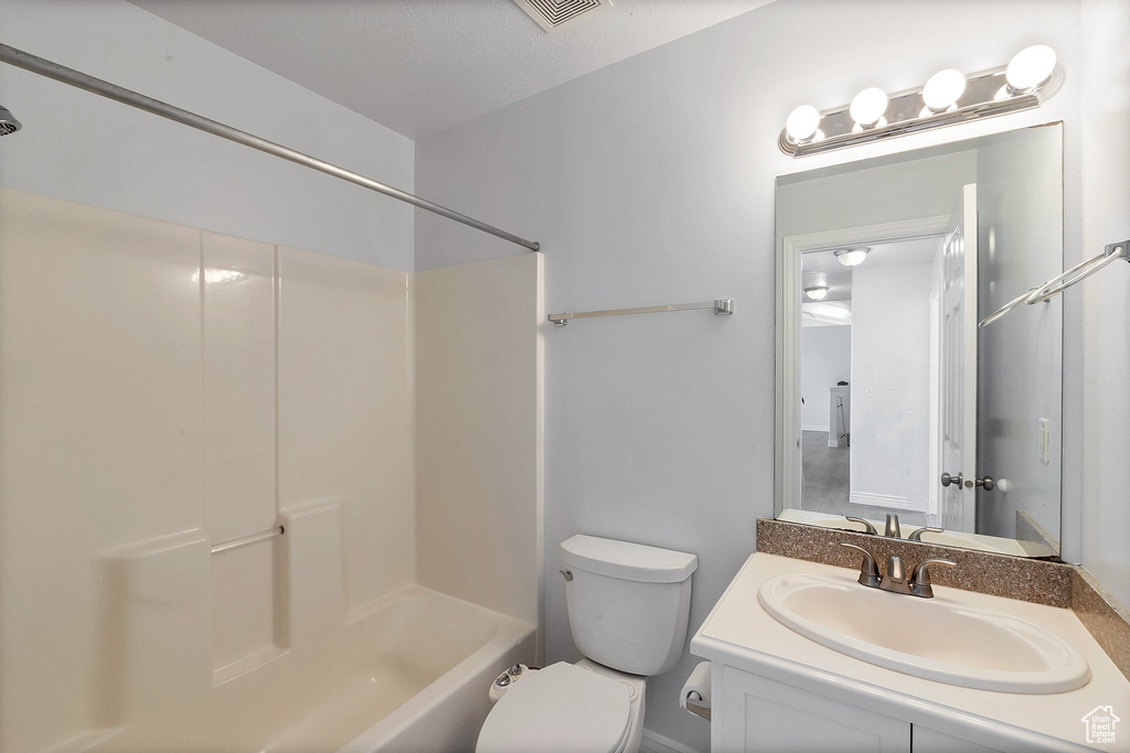 Full bathroom featuring a textured ceiling, toilet, washtub / shower combination, and vanity with extensive cabinet space