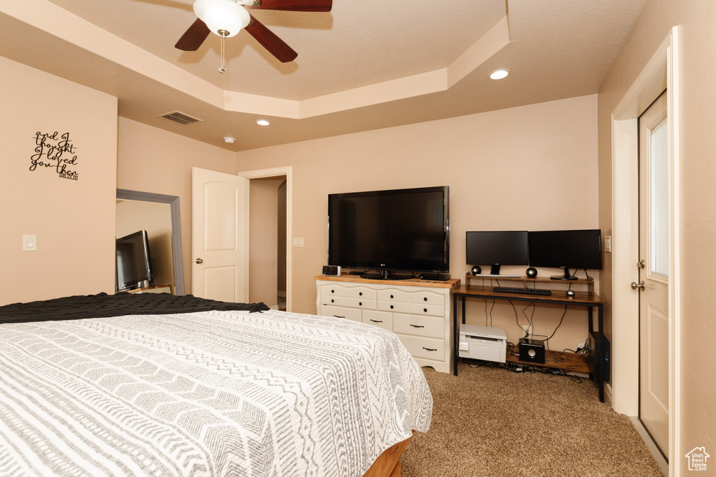 Bedroom featuring ceiling fan, carpet flooring, and a tray ceiling