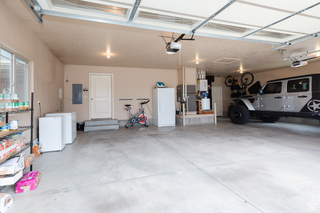 Garage featuring a garage door opener and white refrigerator