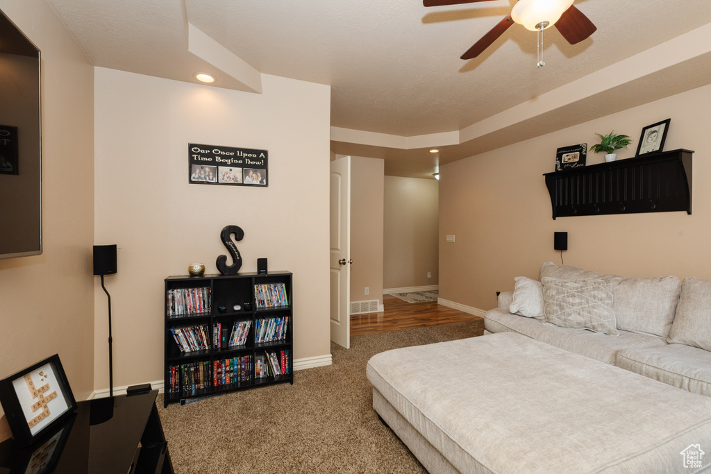 Bedroom with ceiling fan, dark colored carpet, and a tray ceiling