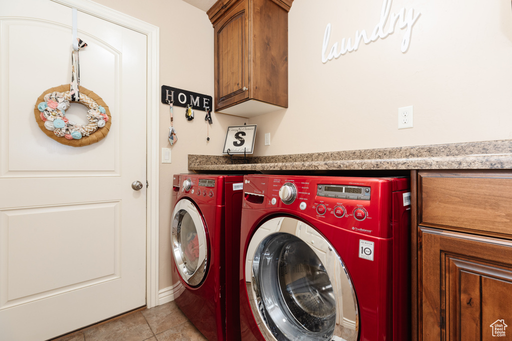 Laundry area with cabinets, separate washer and dryer, and light tile floors