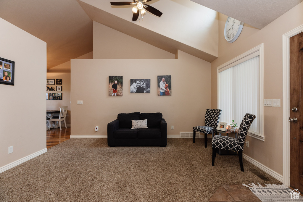 Sitting room featuring vaulted ceiling, ceiling fan, and dark colored carpet
