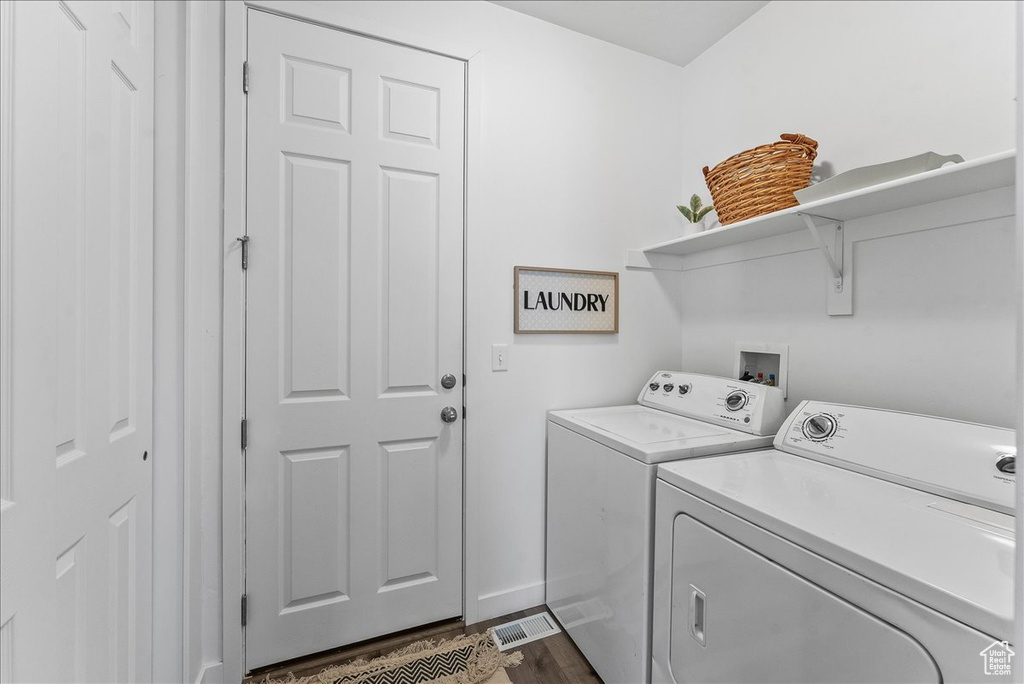 Laundry area with dark wood-type flooring, separate washer and dryer, and hookup for a washing machine