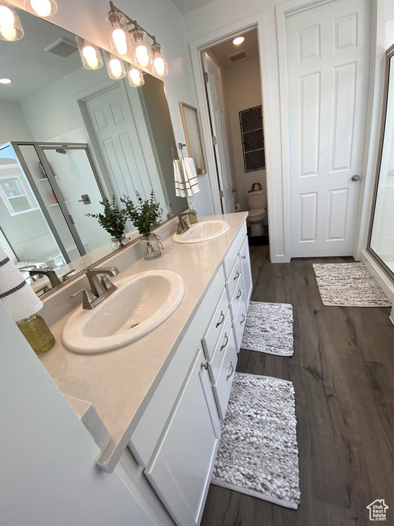 Bathroom featuring hardwood / wood-style floors, double sink, toilet, and large vanity