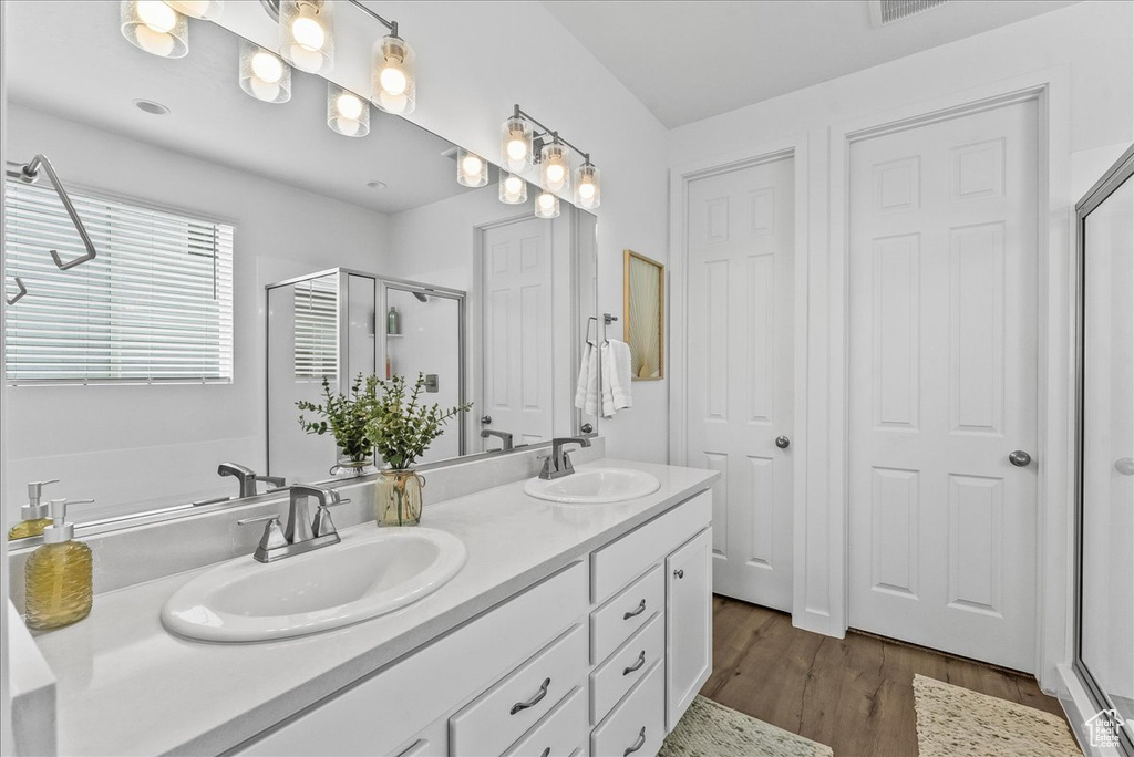 Bathroom with an enclosed shower, oversized vanity, dual sinks, and hardwood / wood-style flooring