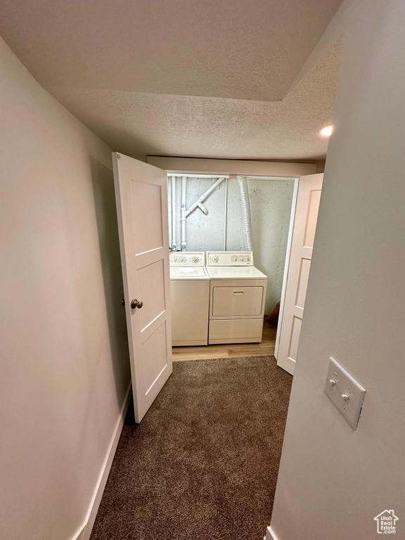 Hall with dark carpet, separate washer and dryer, and a textured ceiling