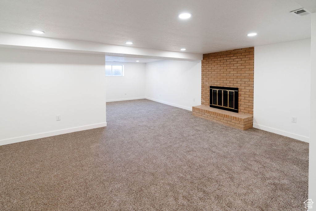 Interior space featuring carpet, brick wall, and a brick fireplace