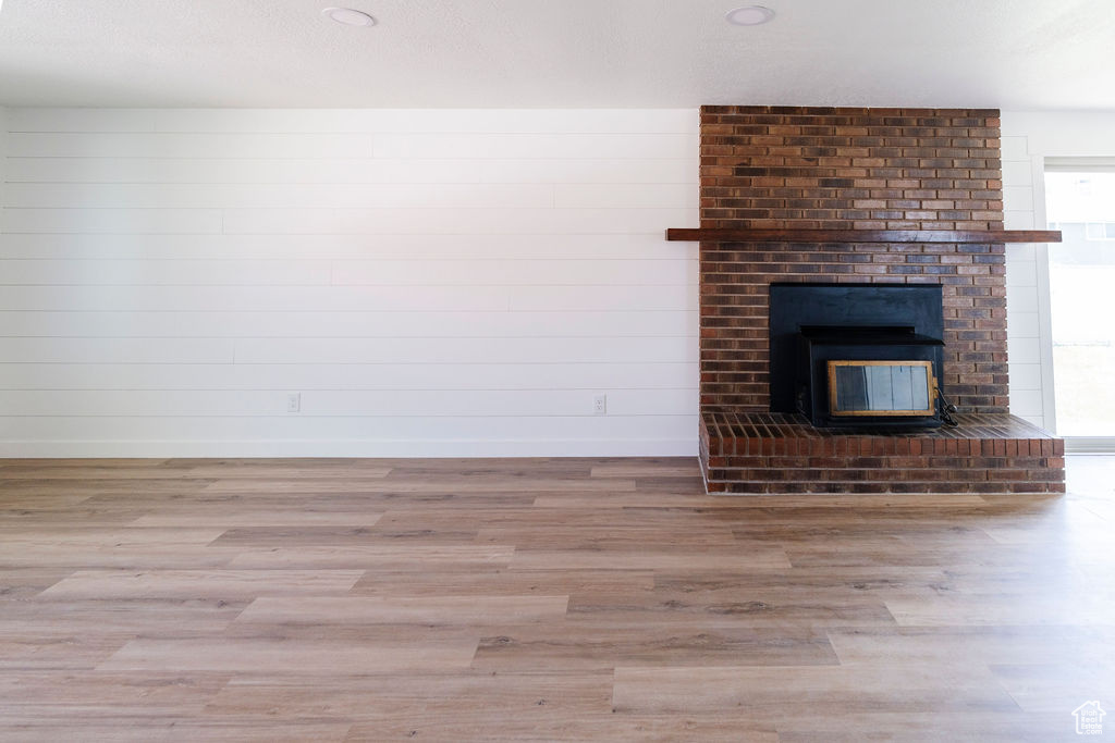 Unfurnished living room featuring brick wall, hardwood / wood-style floors, and a fireplace
