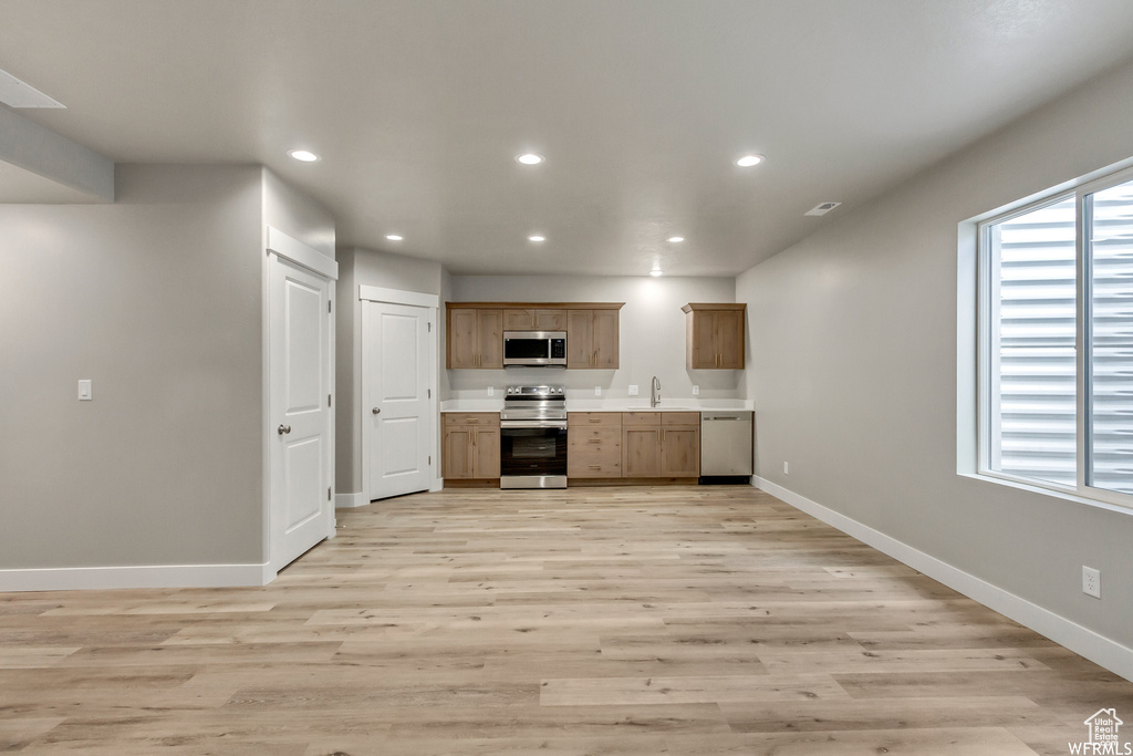 Kitchen with light hardwood / wood-style flooring, appliances with stainless steel finishes, a healthy amount of sunlight, and sink