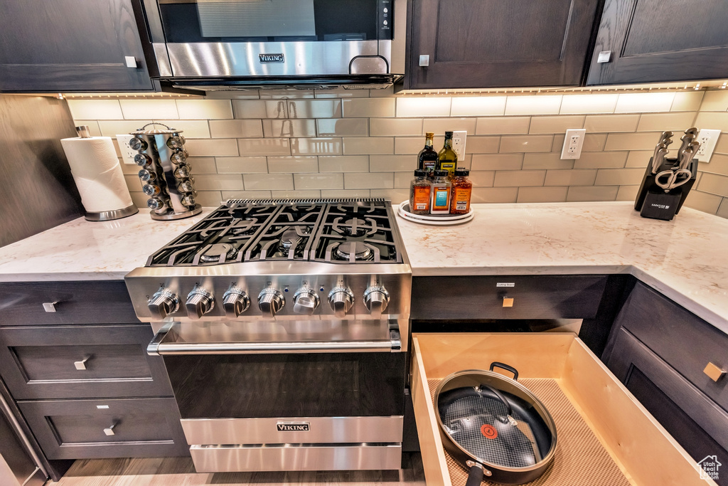 Kitchen featuring backsplash, stainless steel appliances, and light stone countertops