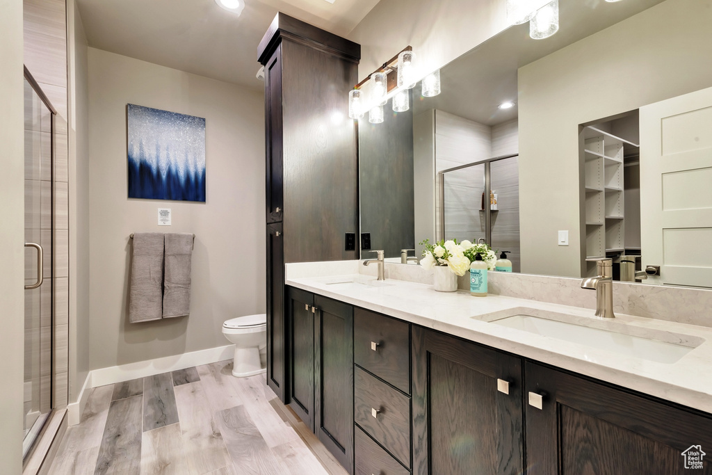 Bathroom featuring walk in shower, toilet, double sink, oversized vanity, and hardwood / wood-style flooring