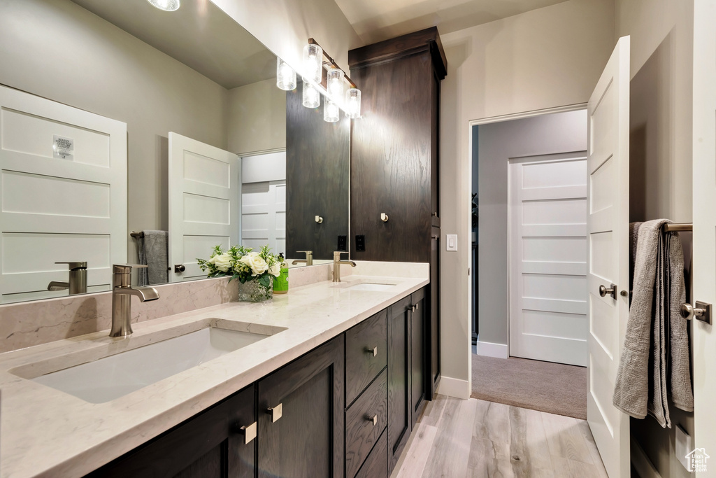 Bathroom with double vanity and wood-type flooring